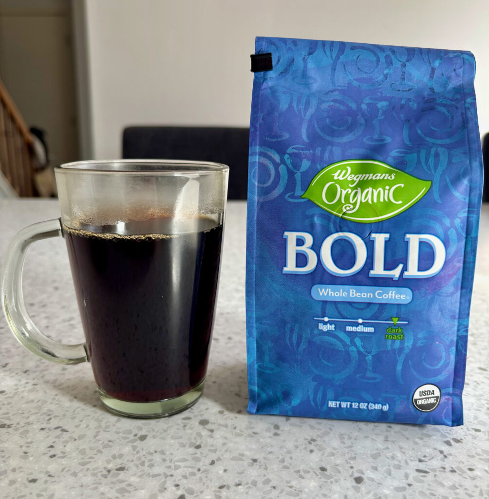 Wegmans Organic Bold Dark Roast Review – freshly brewed cup of coffee next to a bag of Wegmans Organic Bold Dark Roast whole bean coffee.
