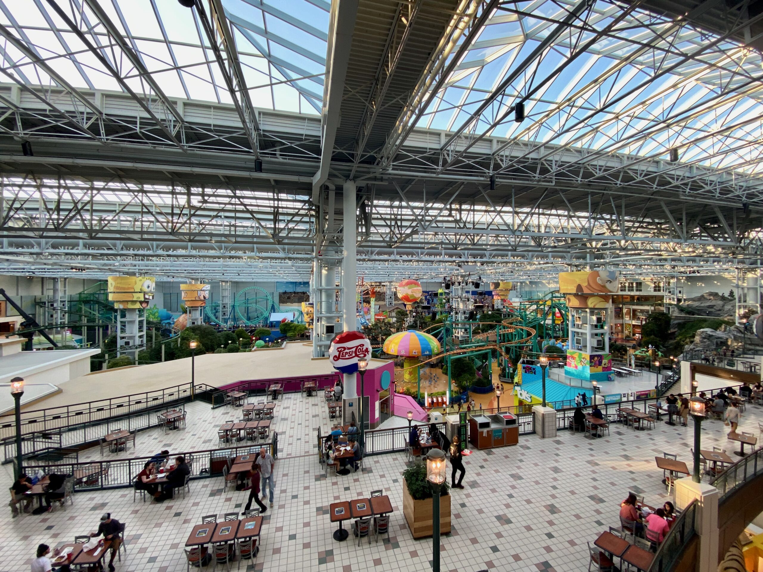 A busy amusement park inside a mall with tables in the foreground