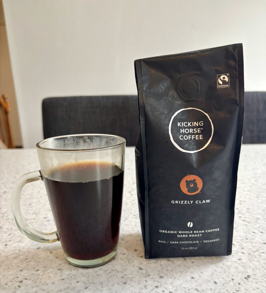 Kicking Horse Coffee Grizzly Claw Review: glass mug of freshly brewed dark roast coffee next to a bag of Kicking Horse Grizzly Claw whole bean coffee on a kitchen countertop
