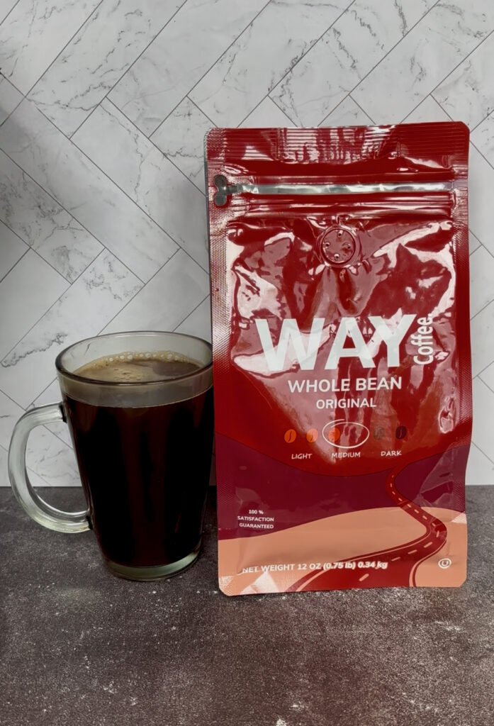 Way Coffee The Original Blend Review featuring a red bag of WAY Coffee Whole Bean Original medium roast next to a clear glass mug filled with freshly brewed black coffee on a kitchen counter.