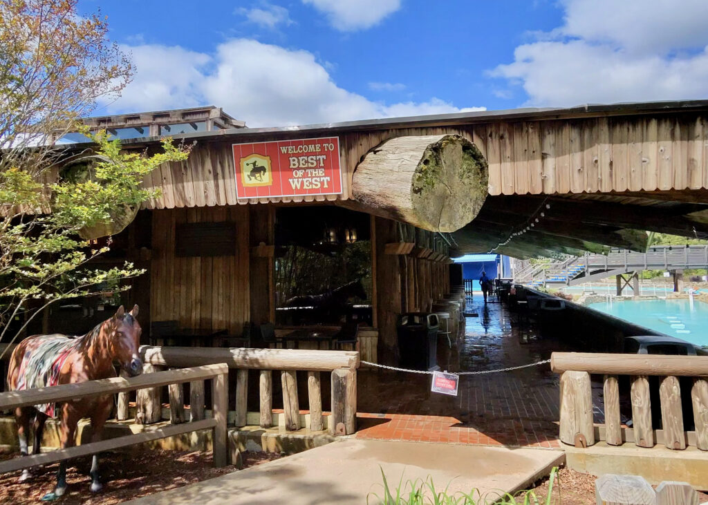 A log building with a sign that says "Welcome to Best of the West" above the entrance and a fake horse to the left for a Six Flags Great Adventure review. 