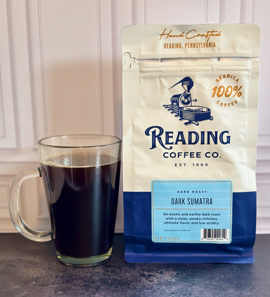 Reading Coffee Company Dark Sumatra Review featuring a bag of Reading Coffee Co. Dark Sumatra beside a freshly brewed mug of dark coffee on a countertop.