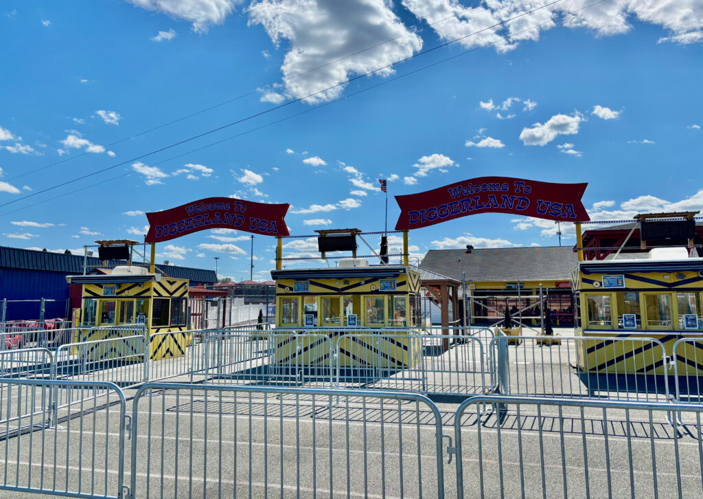 Diggerland USA Review main photo showing the yellow ticket boxes of the park with red signs on top that say "Welcome to Diggerland USA"