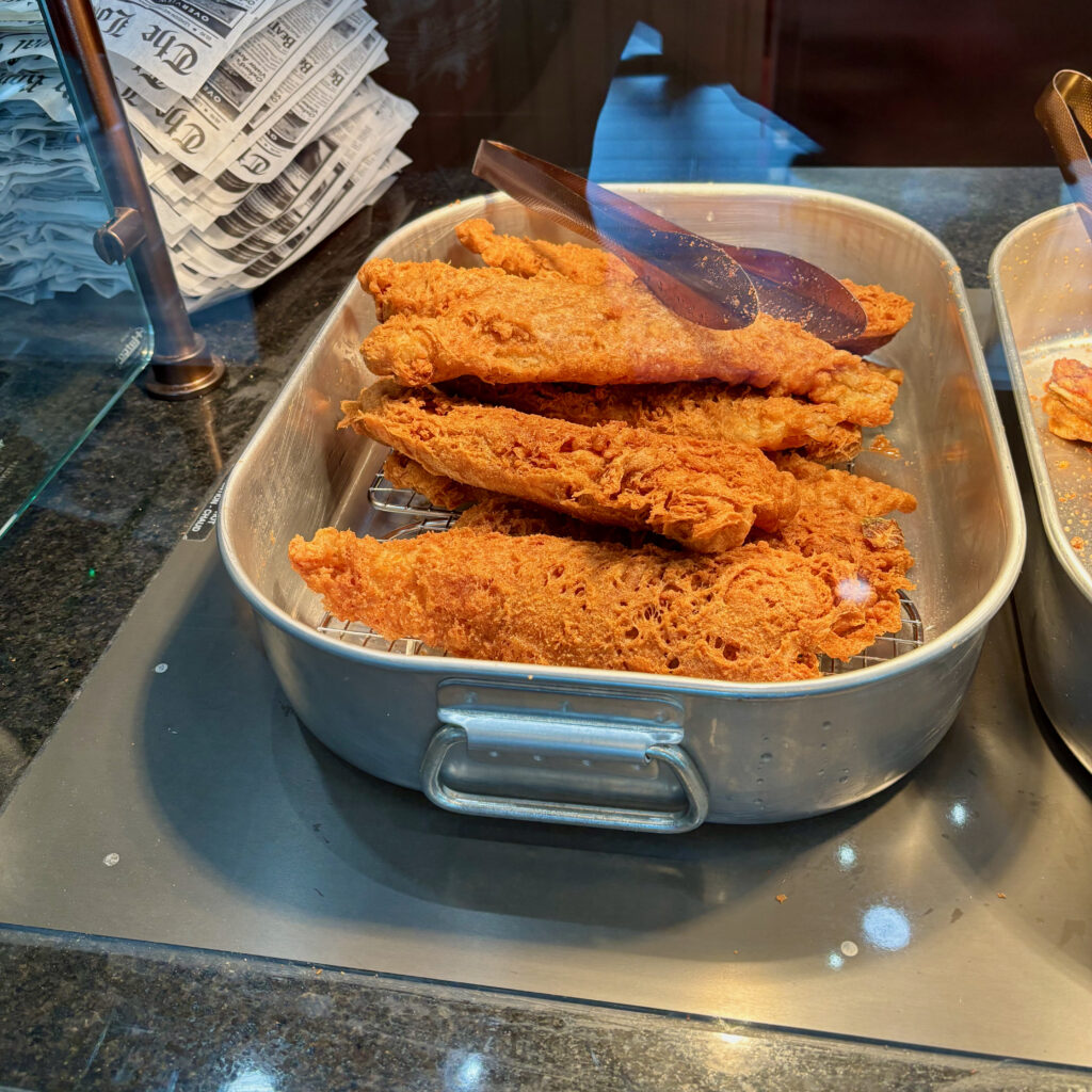 Six Flags Great Adventure review showing large fried fish fillets for the fish and chips meal behind the serving counter.