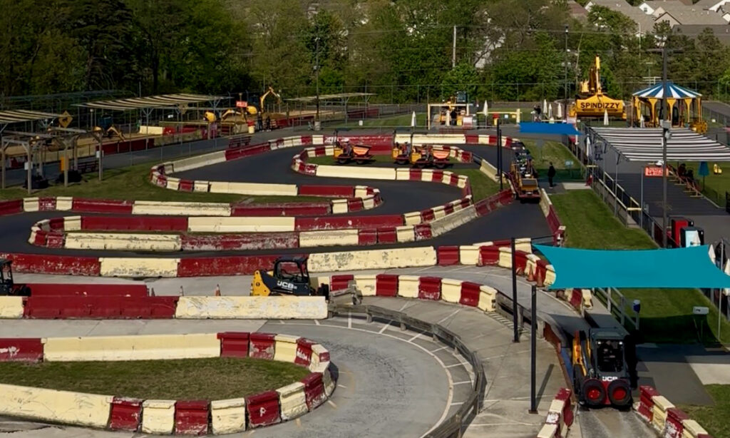 Diggerland USA Review photo showing skid steers, dump trucks, excavators, a JCB lift, and Spin Dizzy a large excavator modified to be a theme park ride. 