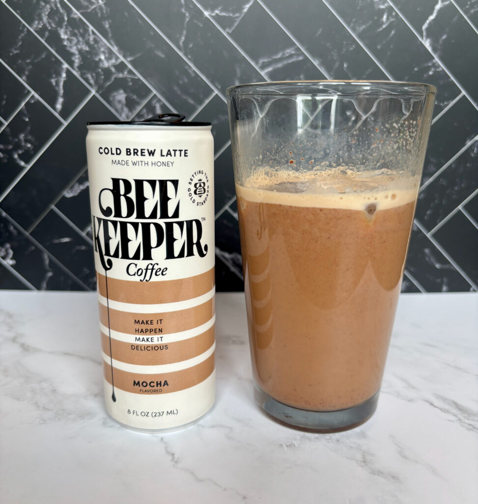 Beekeeper Coffee Cold Brew Mocha Latte can next to a glass of poured iced coffee for this Beekeeper Coffee Cold Brew Mocha Latte review
